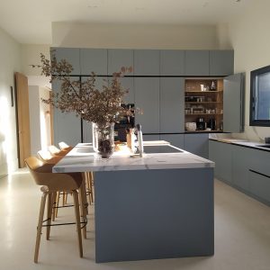 Cocina ‘open space’ con muebles en color azul y encimera con acabado en mármol